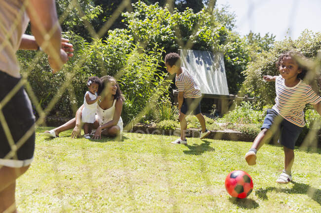 Glückliche Familie spielt Fußball im sonnigen Sommergarten — Stockfoto