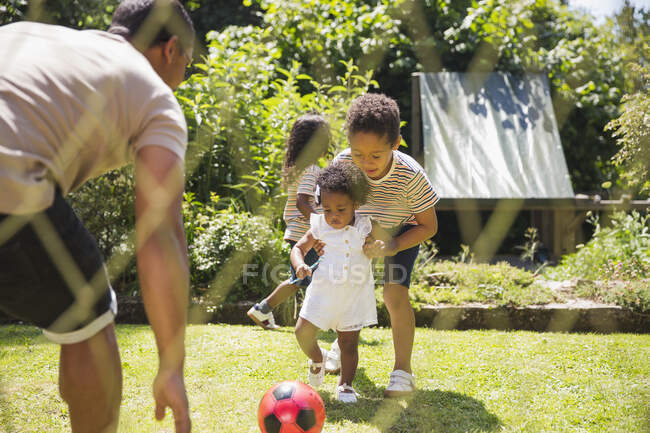 Family playing soccer in sunny summer backyard — Stock Photo