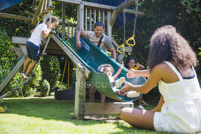 Family playing at play structure in sunny summer backyard — Stock Photo
