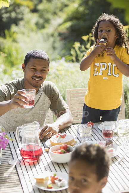 Vater und Kinder genießen Mittagessen im Garten auf sonniger Sommerterrasse — Stockfoto