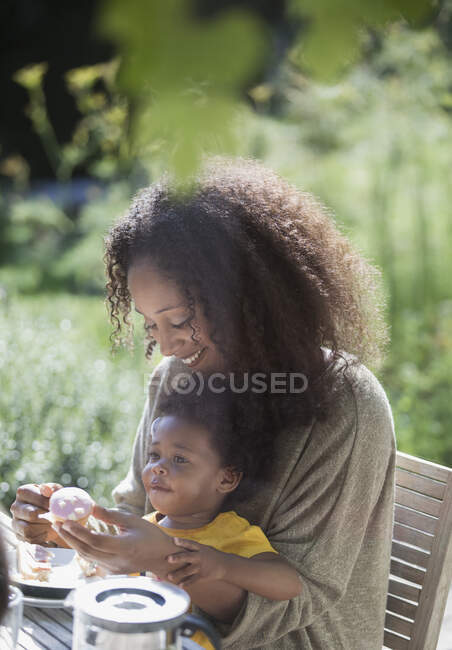 Madre e figlia bambino mangiare al soleggiato patio estivo — Foto stock