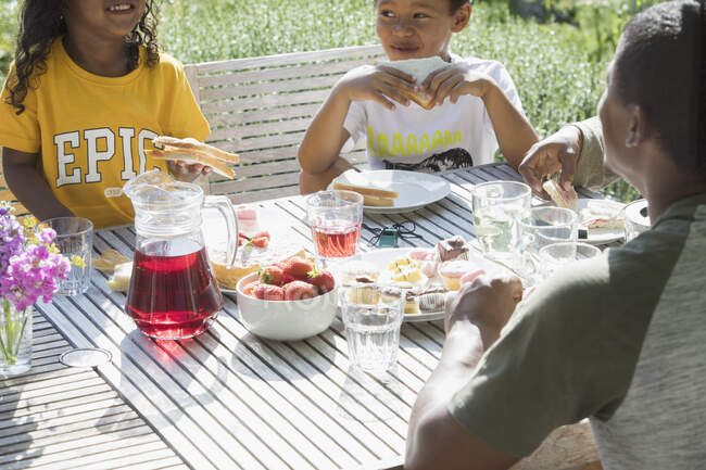 Family eating lunch at sunny summer patio table — Stock Photo