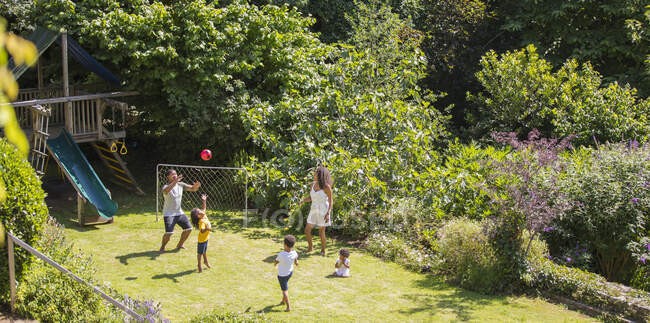 Familie spielt Fußball im sonnigen Sommergarten — Stockfoto