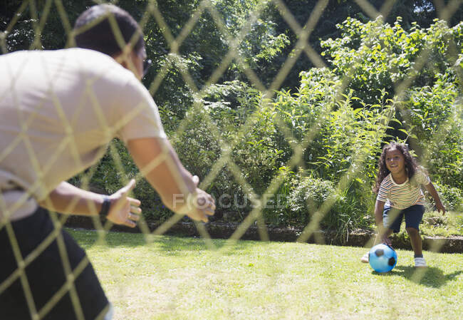 Vater und Tochter spielen Fußball im sonnigen Sommergarten — Stockfoto
