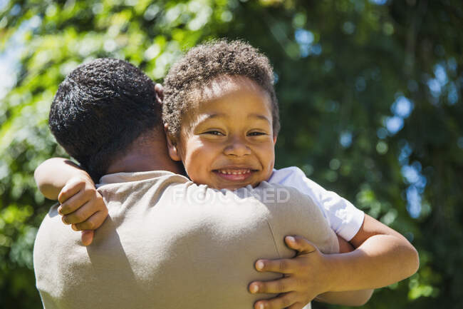 Portrait heureux fils étreignant père au soleil — Photo de stock