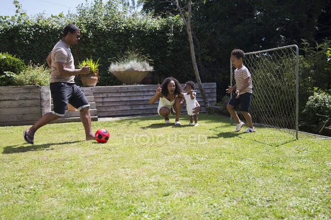 Familie spielt Fußball im sonnigen Sommergarten — Stockfoto