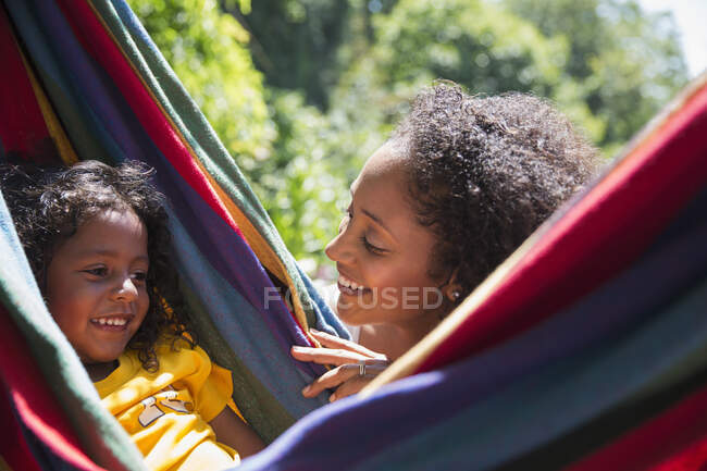 Happy mother watching daughter in sunny summer hammock — Stock Photo