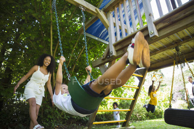 Счастливая семья катается и играет на детской площадке, установленной в летнем дворе — стоковое фото
