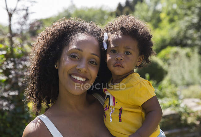Portrait happy mother and toddler daughter in sunny yard — Stock Photo