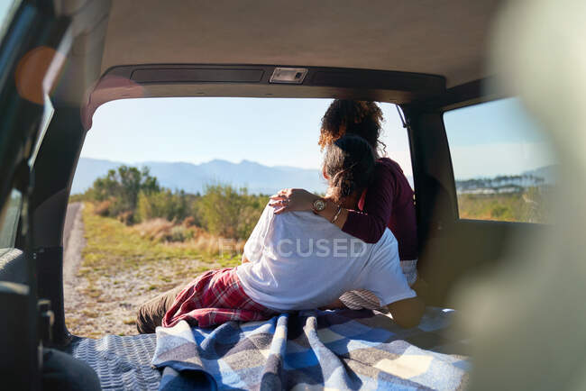 Liebevolles junges Paar genießt sonnige Aussicht von der Rückseite des Autos — Stockfoto