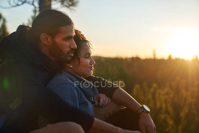 Прихильна спокійна молода пара розслабляється в природі на заході сонця — стокове фото