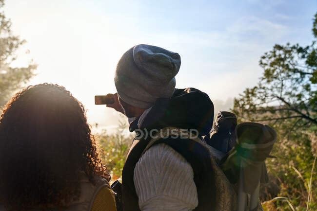 Молода пара ходить і використовує телефон в сонячному лісі — стокове фото