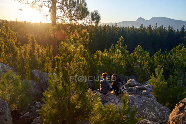 Jovem casal caminhadas relaxante na rocha em bosques cênicos ensolarados — Fotografia de Stock