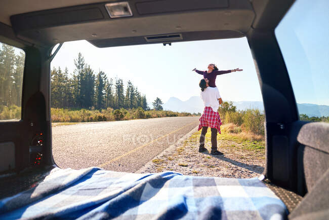 Despreocupado jovem casal fora do carro na ensolarada beira da estrada remota — Fotografia de Stock