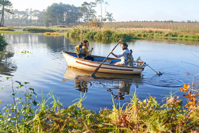 Coppia giovane in barca a remi sul fiume soleggiato — Foto stock