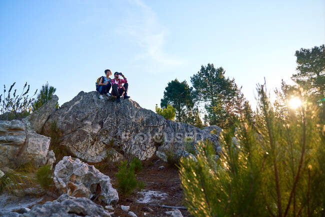 Jovens caminhadas casal relaxante na rocha na natureza ensolarada — Fotografia de Stock