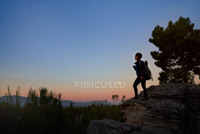 Young female hiker on rock in scenic tranquil desert at dusk — Stock Photo