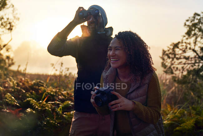 Felice giovane coppia escursionistica con macchina fotografica e binocolo in natura — Foto stock