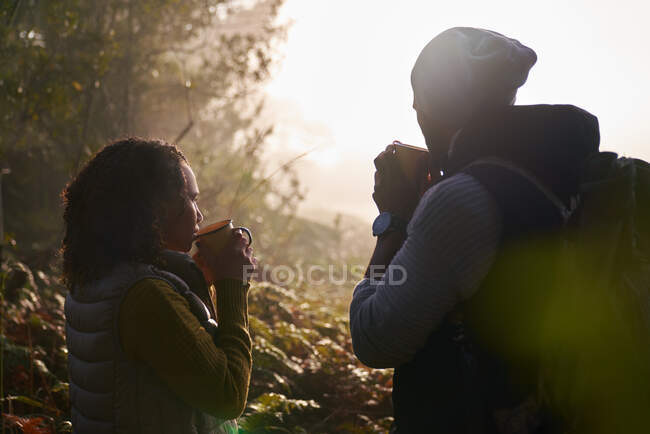 Silhouette young couple drinking coffee in autumn nature — Stock Photo