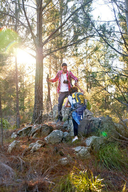 Young couple hiking up slope in sunny woods — Stock Photo