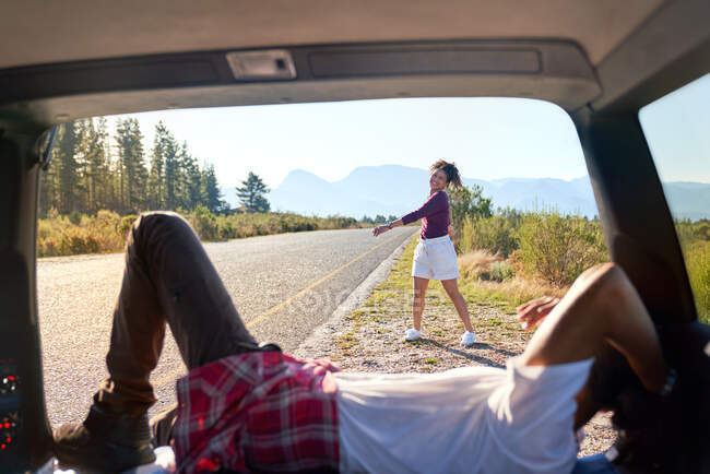 Счастливая беззаботная пара отдыхает снаружи автомобиля на солнечной удаленной дороге — стоковое фото