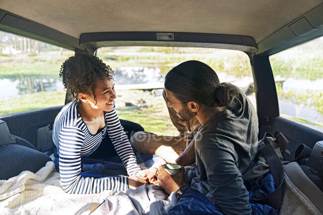 Happy affectionate young couple relaxing in back of car on road trip — Stock Photo