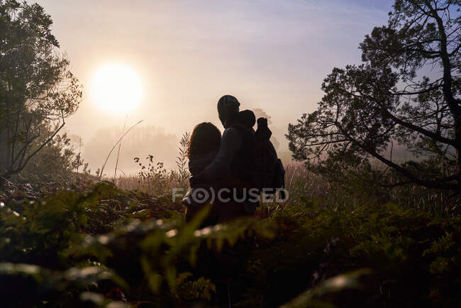 Silhouette sereine jeune couple profitant du coucher de soleil dans la nature — Photo de stock