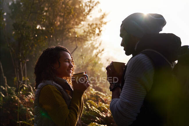 Feliz jovem caminhadas casal beber café na floresta ensolarada — Fotografia de Stock