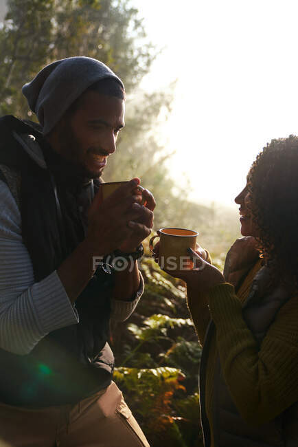 Feliz jovem caminhante casal beber café na floresta ensolarada — Fotografia de Stock