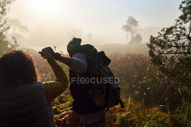 Junges Paar hält Händchen und wandert im hohen Gras bei Sonnenuntergang — Stockfoto