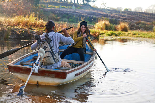 Heureux jeune couple avec des rames en barque sur le lac ensoleillé d'automne — Photo de stock