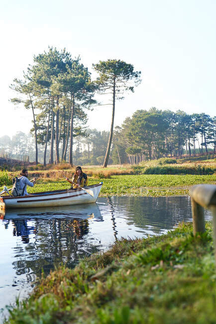 Jeune couple en barque sur étang tranquille ensoleillé — Photo de stock
