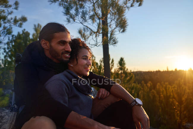 Carinhoso jovem caminhante casal desfrutando do pôr do sol na floresta — Fotografia de Stock