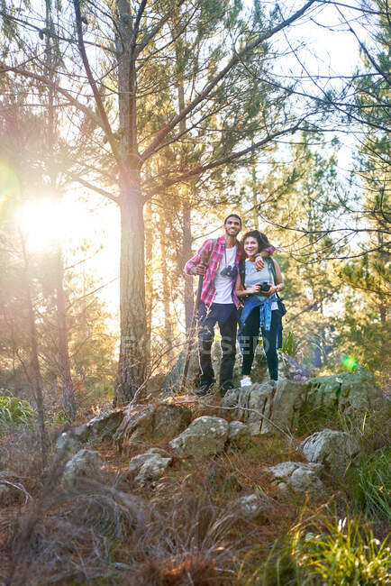 Feliz joven pareja de senderismo en bosques soleados - foto de stock