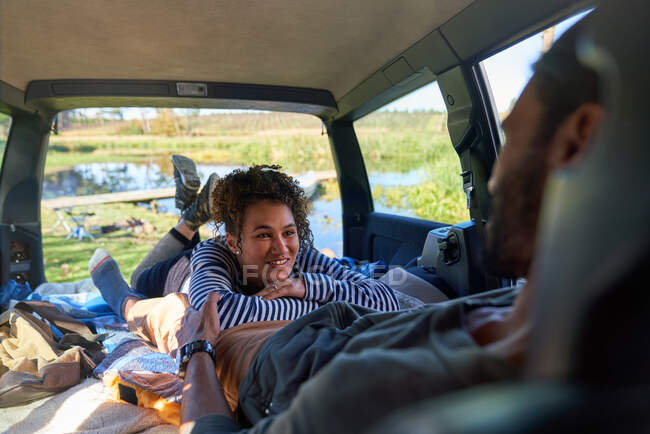 Feliz jovem casal relaxante e camping dentro de volta do carro — Fotografia de Stock
