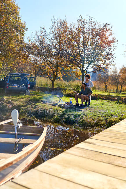 Casal jovem acampar ao lado do lago de outono ensolarado — Fotografia de Stock