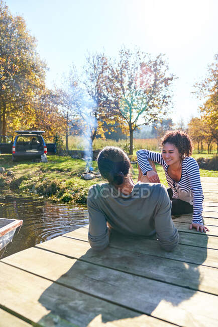 Feliz casal jovem relaxante na ensolarada doca de outono perto do acampamento — Fotografia de Stock