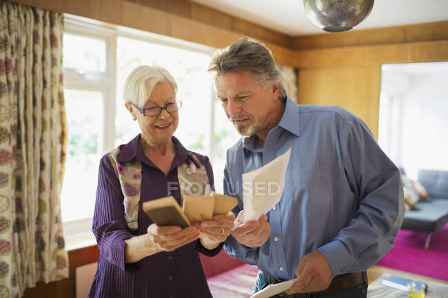 Senior couple looking at wood and paint swatches in living room — Stock Photo