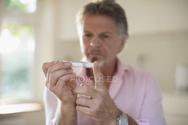 Uomo anziano con diabete che utilizza misuratore di glucosio nel sangue sul dito — Foto stock