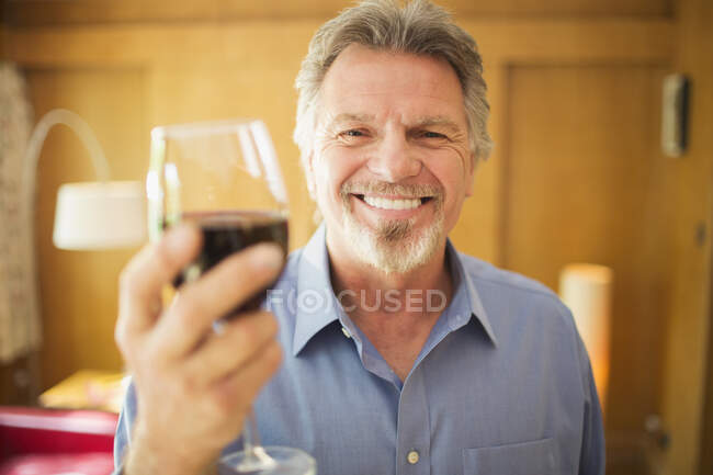 Счастливый беззаботный пожилой человек пьет красное вино — стоковое фото
