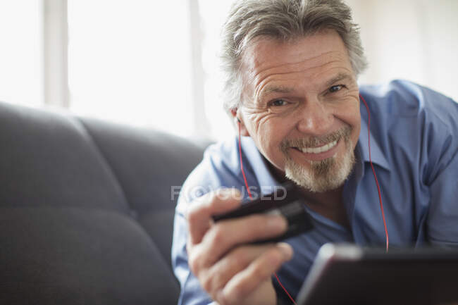 Портрет улыбающегося пожилого человека с наушниками и кредиткой — стоковое фото