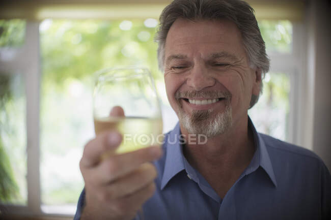 Primer plano sonriente hombre mayor bebiendo vino blanco - foto de stock