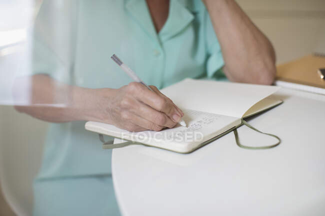 Großaufnahme Seniorin schreibt in Tagebuch am Tisch — Stockfoto