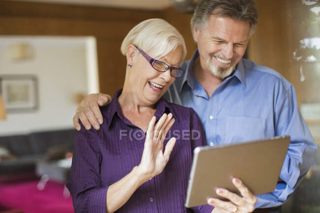 Feliz casal sênior vídeo bate-papo com tablet digital em casa — Fotografia de Stock