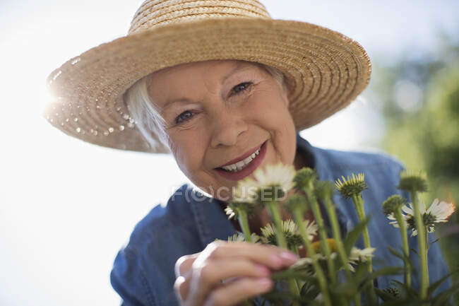 Primer plano retrato feliz mujer mayor jardinería en sombrero de paja - foto de stock