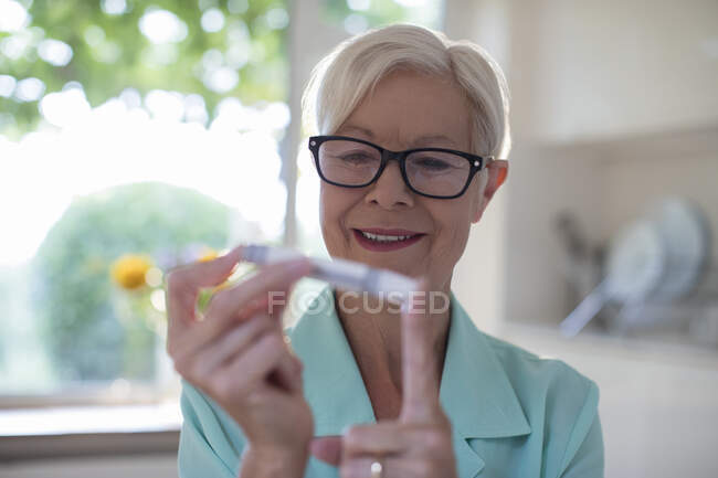 Senior woman with diabetes using blood glucose meter on finger — Stock Photo