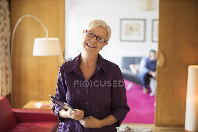 Ritratto felice donna anziana sicura di sé con tablet digitale in soggiorno — Foto stock
