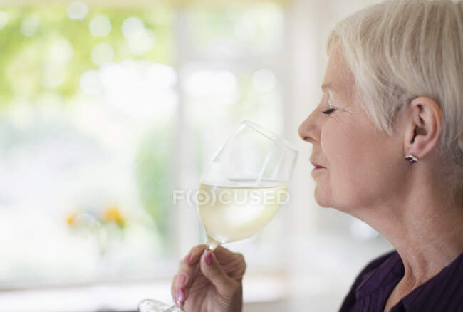 Serena donna anziana odore e degustazione di vino bianco — Foto stock