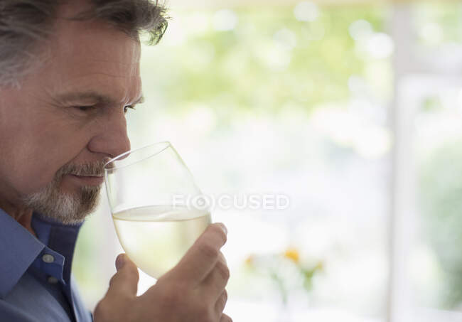 Close up senior man smelling and tasting white wine — Stock Photo
