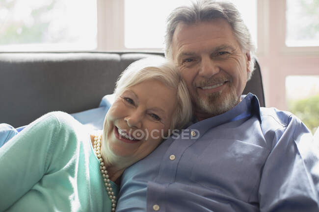 Portrait happy senior couple cuddling on living room sofa — Stock Photo